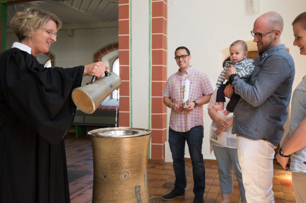 Wasser wird aus einer Kanne in die Taufschale gegossen